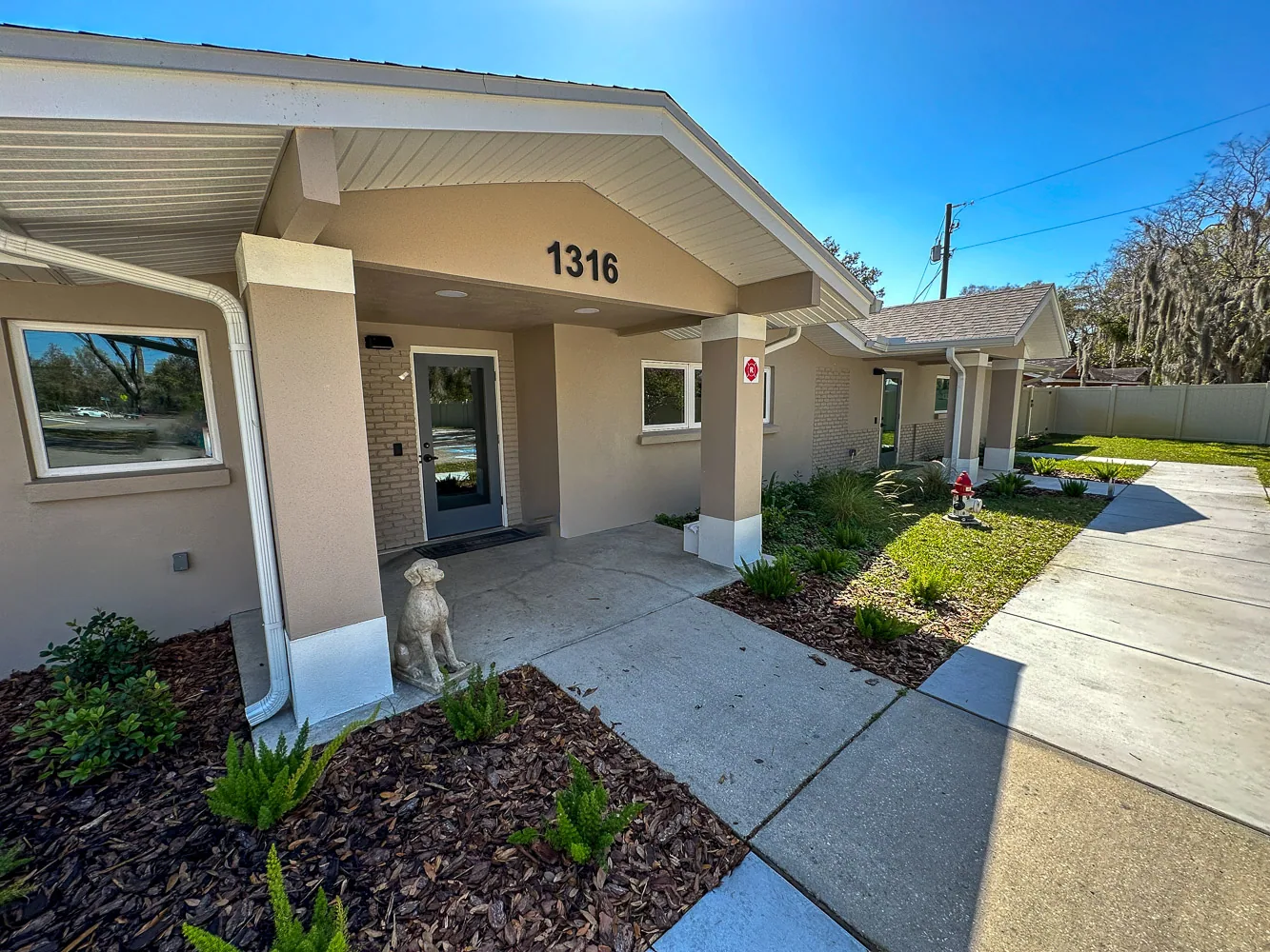 Veterinary clinic exterior featuring welcoming entrance with house number 1316, decorative dog statue, and landscaped garden, emphasizing Gregory Veterinary Clinic's commitment to pet care.
